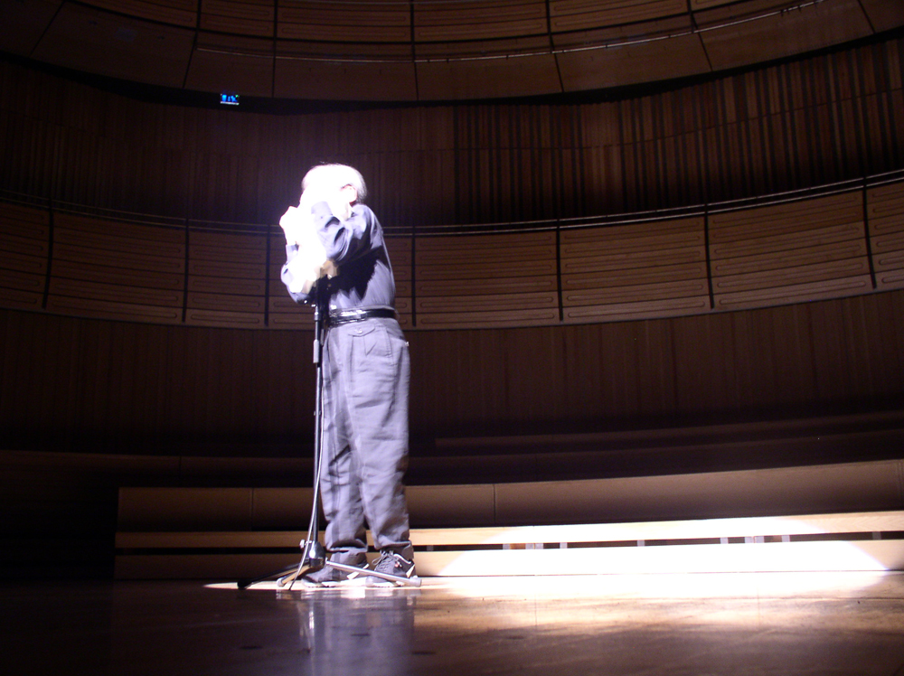 Takehisa Kosugo wraps a sheet of paper tightly around a microphone