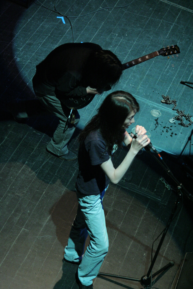Junko singing into a microphone & Masayoshi Urabe playing a guitar