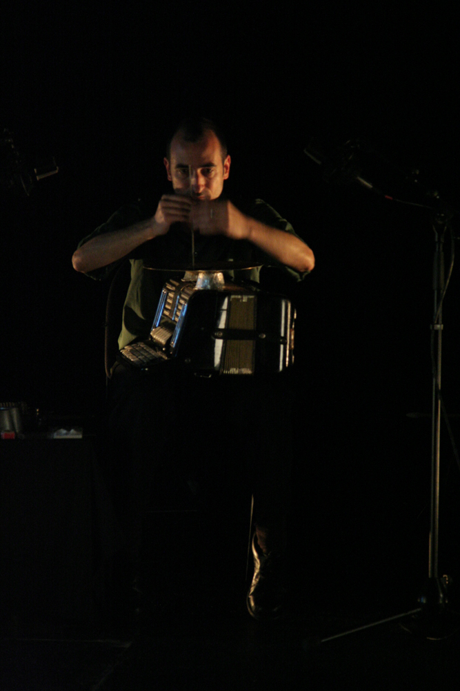 Alfredo concentratedly holding a small stick against an accordion 