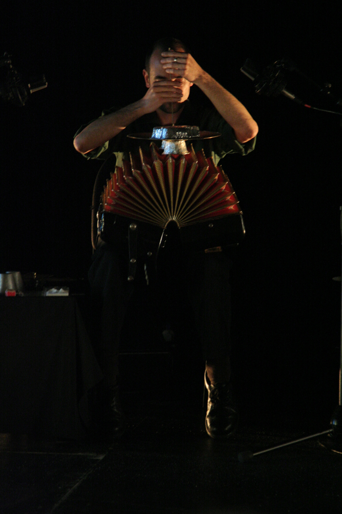 Alfredo concentratedly holding a small stick against an accordion 