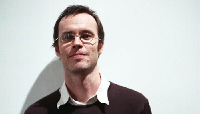 Anthony Burr wearing glasses, white shirt and jumper