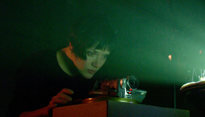 Emma Hart lit from the glare of a projector as she adjusts a camera