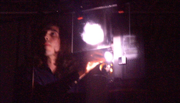 Luis recoder's face lit from the side by a projector