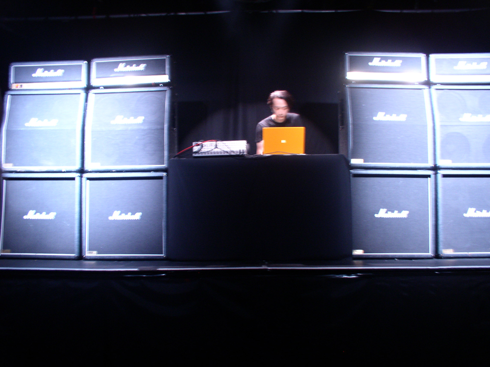 Rioji Ikeda operating a laptop surrounded by Marshall amplifiers