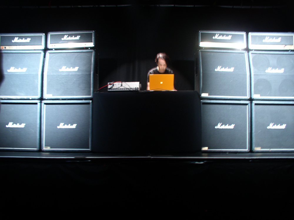 Rioji Ikeda operating a laptop surrounded by Marshall amplifiers