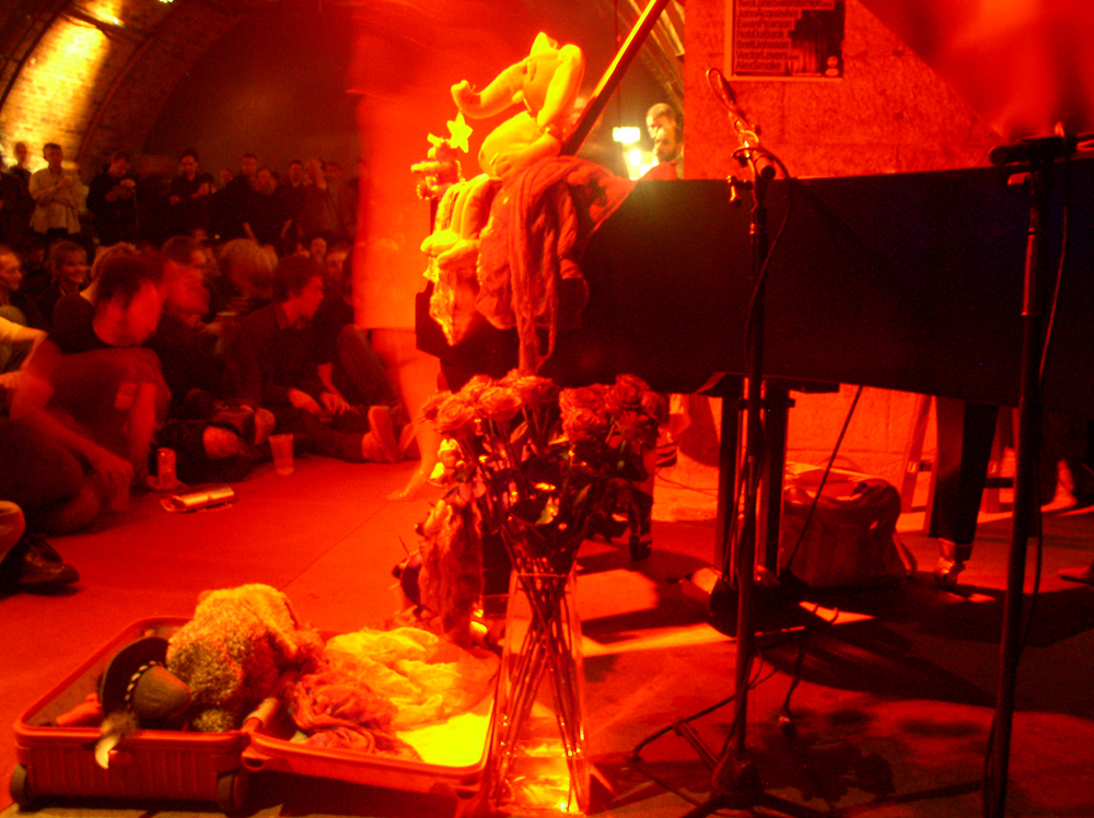 Charlemagne's piano covered in soft toys and red light