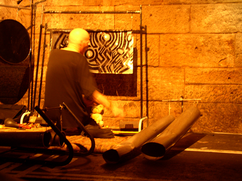 Z'EV performing with home made percussion instruments in a railway arch