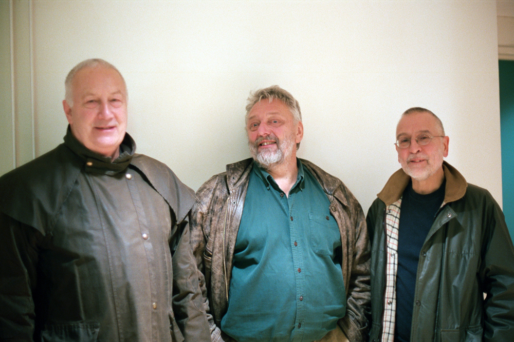 John Tilbury, Malcolm Le Grice and Eddie Prevost standing near a wall