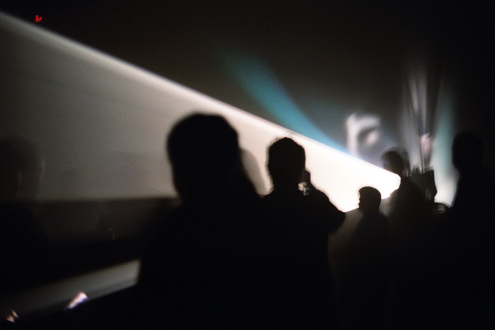A cone of light among audience members in silhouette 