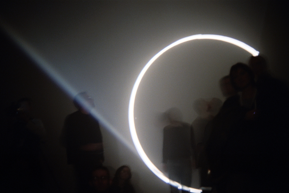 A circle of light from a projector circles audience members