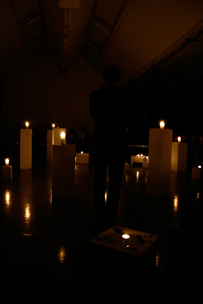 A room full of plinths with candles on top