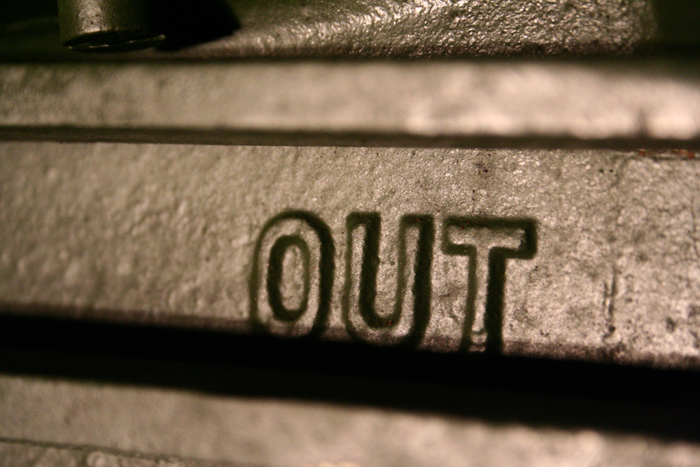 Close up of a metallic form with the word 'OUT' in relief 