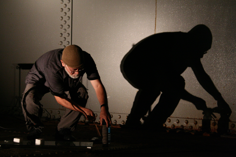 Akio Suzuki and shadow moving things around on the floor of an oil tank