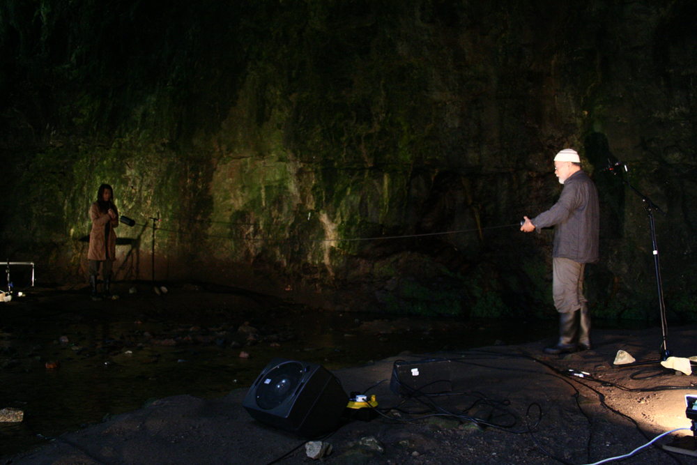 Akio Suzuki stretching a spring across the entrance to a cave