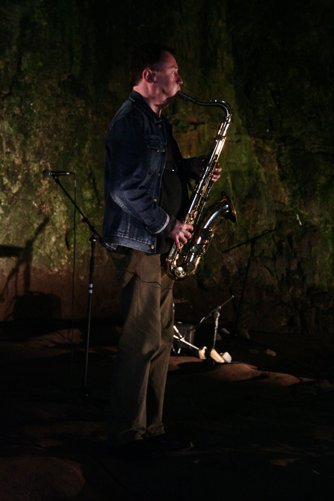 John Butcher playing a tenor saxophone in smoo cave