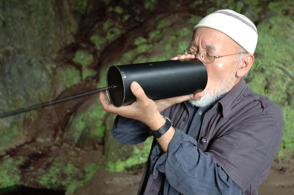 Akio Suzuki blowing into a metal can + spring in a cave