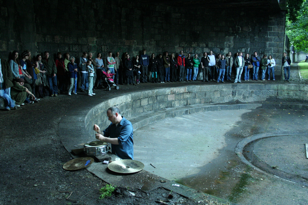 An audience assembled around a curved enclosed stone space