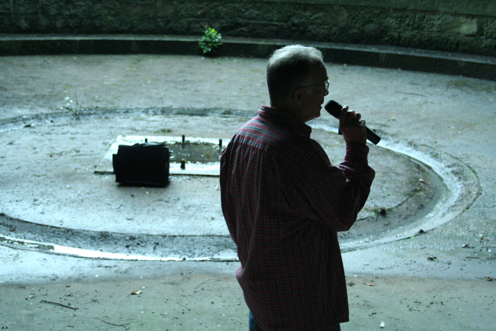 Denis Wood talking into a microphone in a little circular space