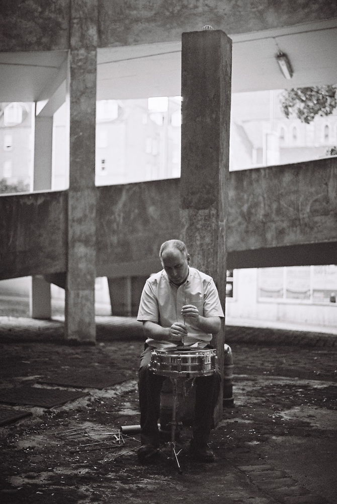 Sean Meehan playing a cymbal with a dowel rod surrounded by concrete forms