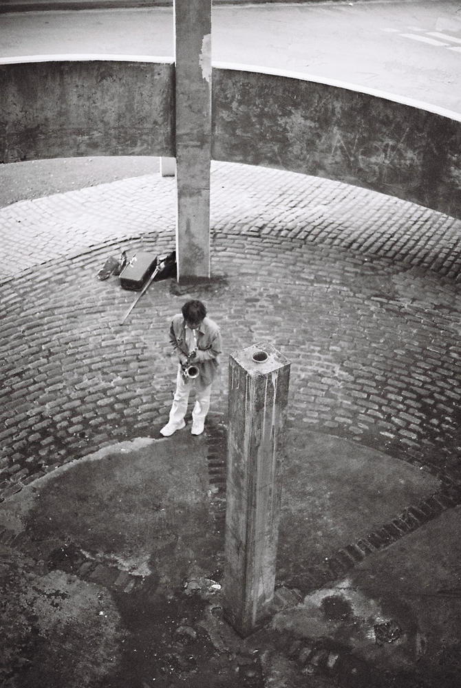 Tamio Shiraishi playing saxophone in a concrete spiral: white jeans white shoes