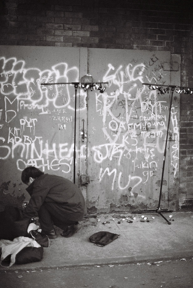 Ikuru Takehashi crouching near a metal door, preparing small devices