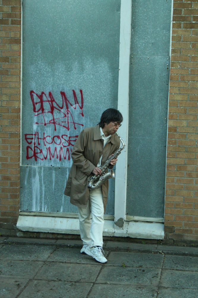 Tamio with saxophone and graffito in Easterhouse 