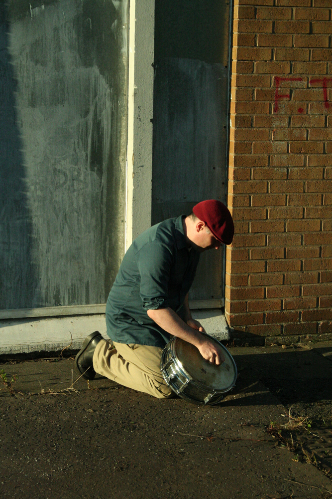 Sean Meehan playing a snare on the ground in the evening