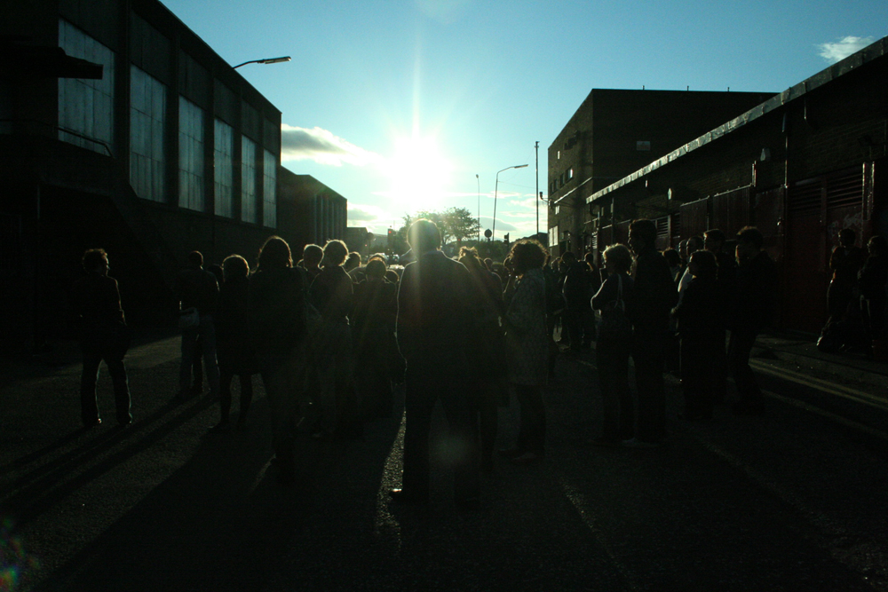 The sun low in the sky above Easterhouse, an audience at a performance