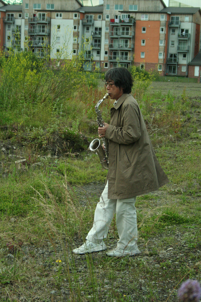 Tamio Shiraishi playing saxophone in a grassy place in Edinburgh
