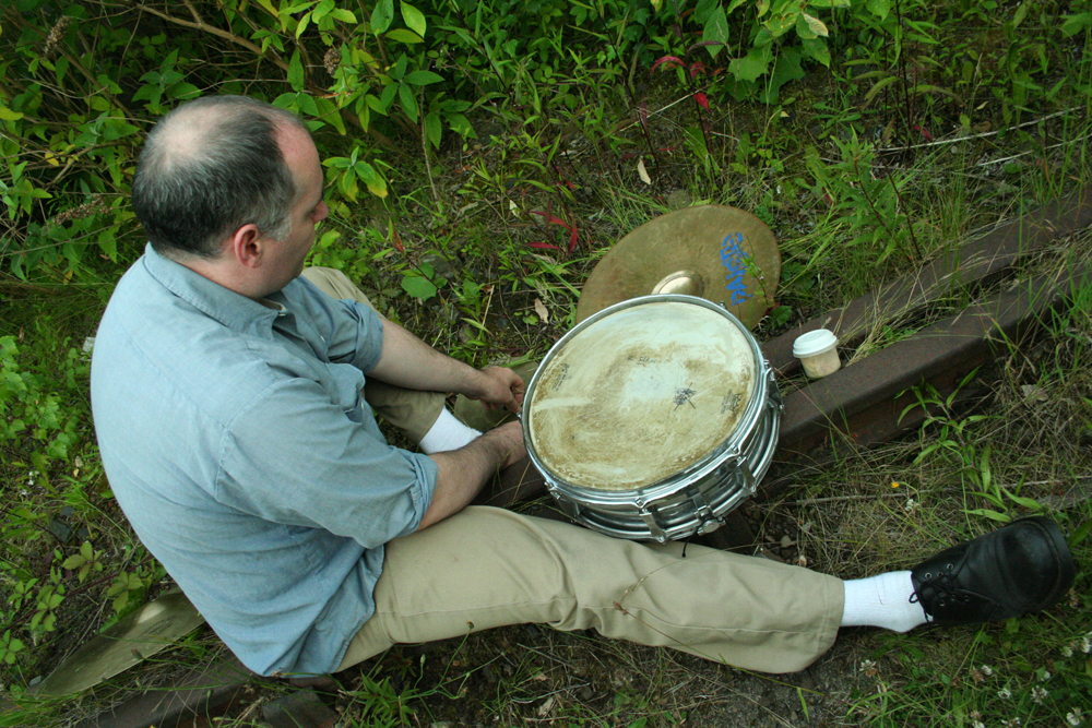 Sean Meehan sitting on a railway track with a snare