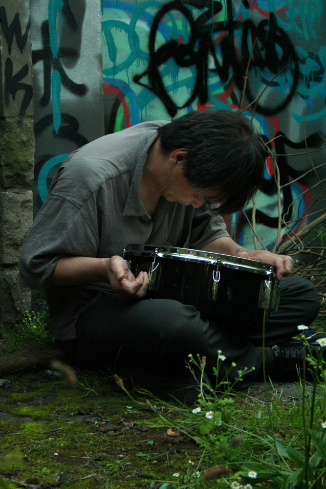 Ikuru Takehashi playing a snare on the ground against a wall