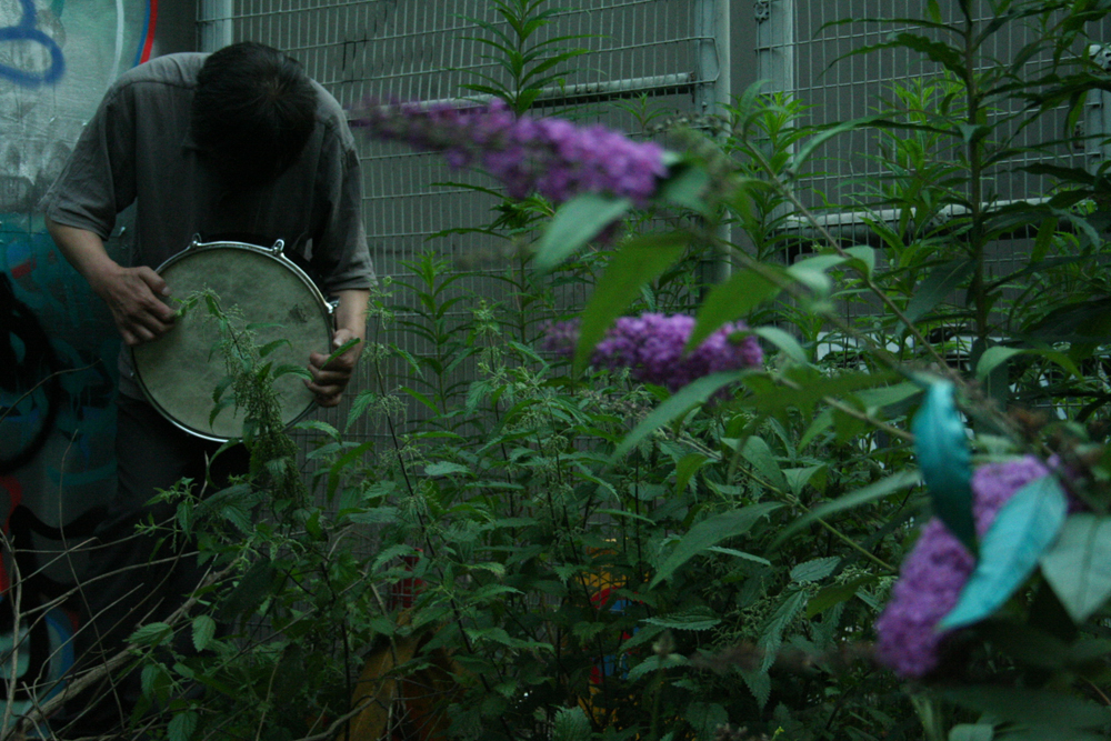 Inure Takehashi playing a snare drum among buddleia 