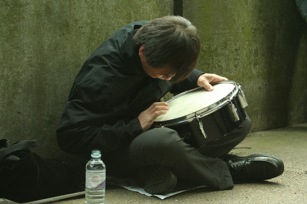 Ikuru Takehashi playing a snare on the ground against a wall