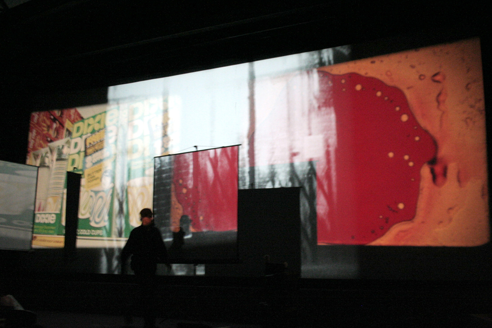 Andrew in silhouette in front of a multi screen projection