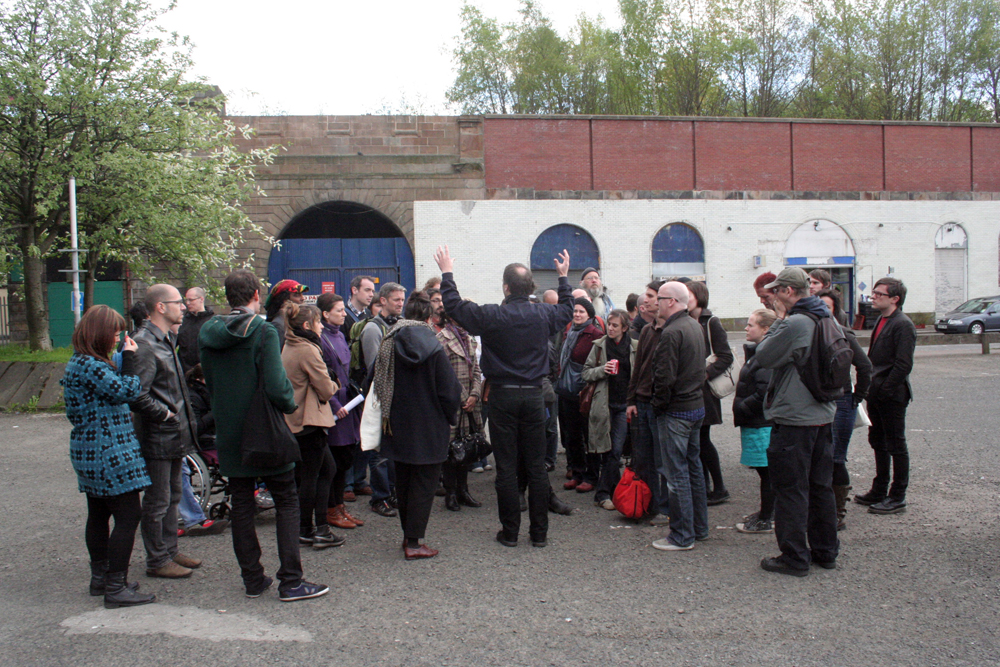 People huddled around a speaker on a street in Glasgow