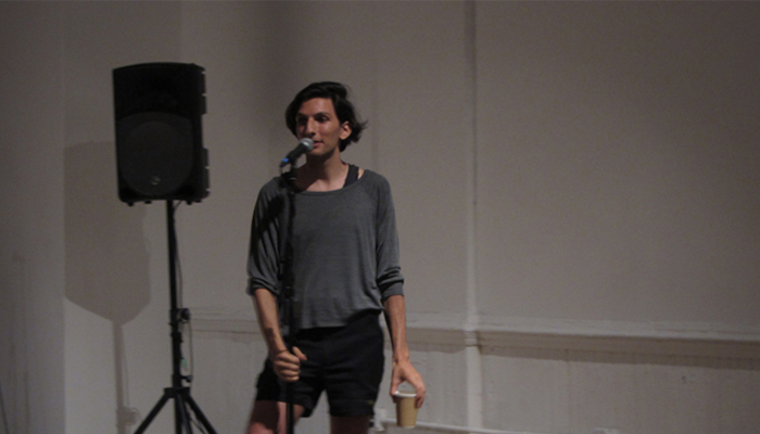 Morgan Bassichis standing behind a microphone speaking