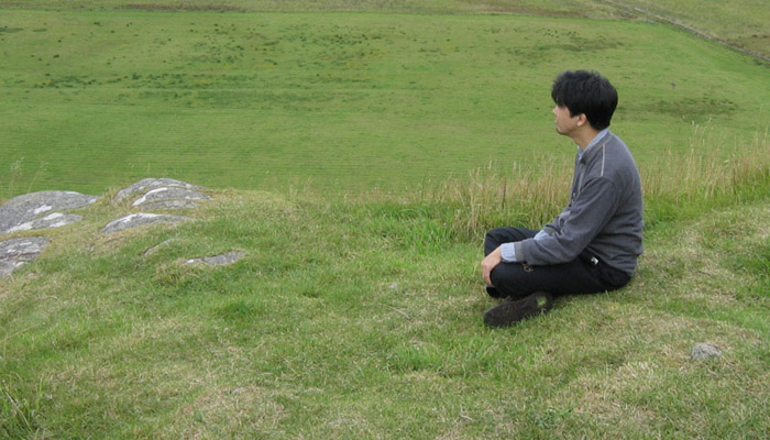Toshia Tsunoda sitting on a grassy knoll in Argyl 