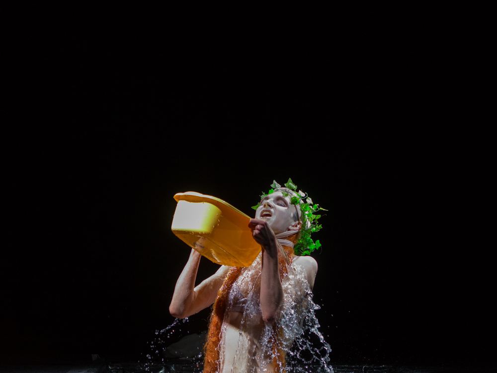 A plastic ivy wreath wearing figure pouring water over herself