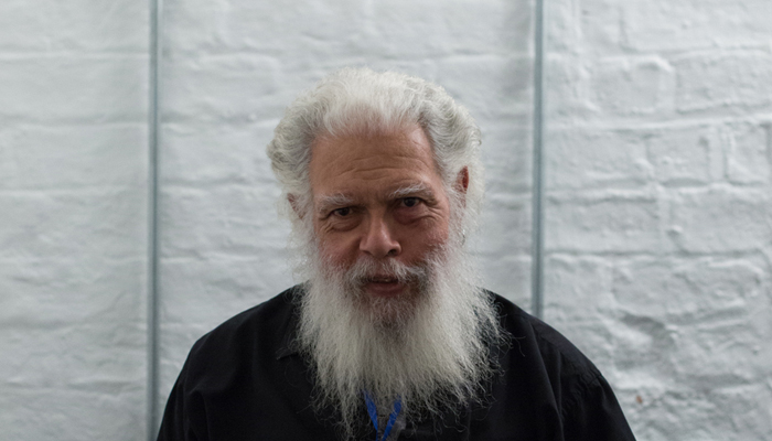 Samuel R Delany pictured backstage against a white wall, bearded