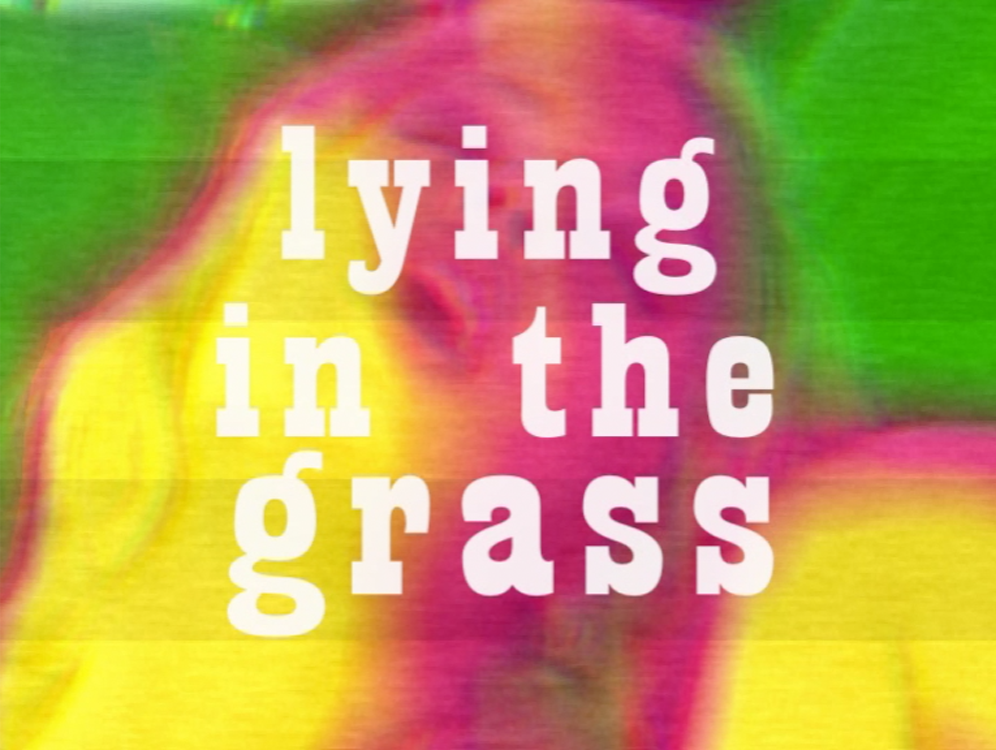 The words "lying in the grass" over an image of a woman's face 