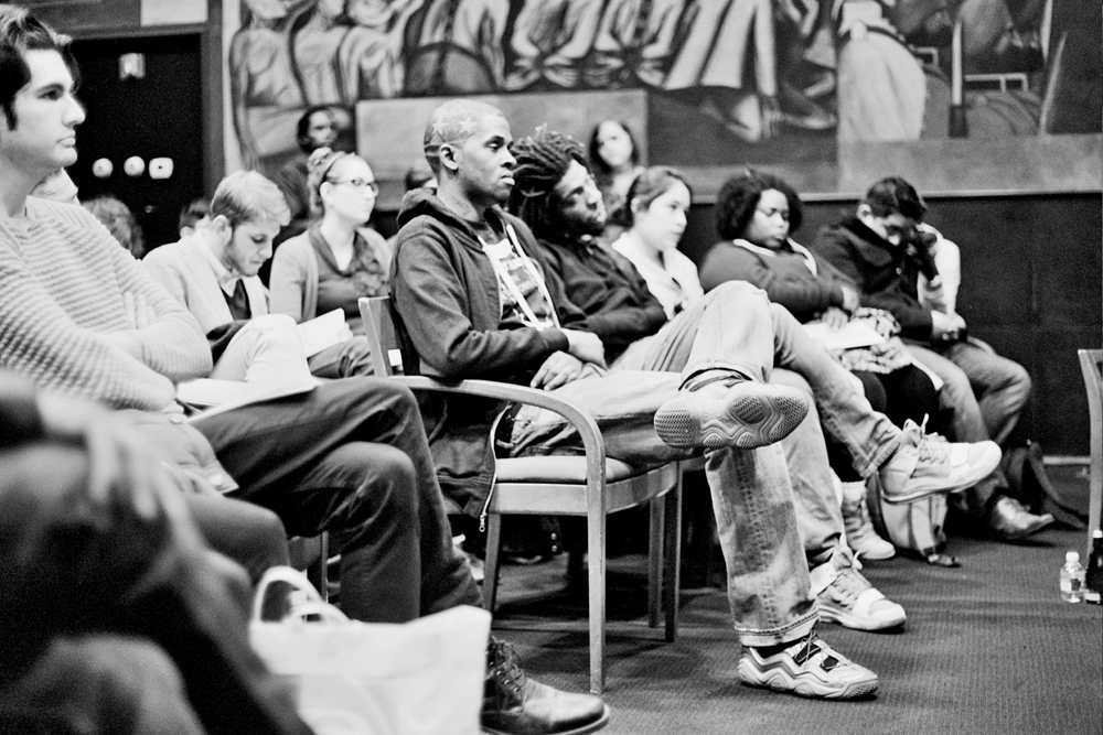 A seated audience listen intently to a panel discussion