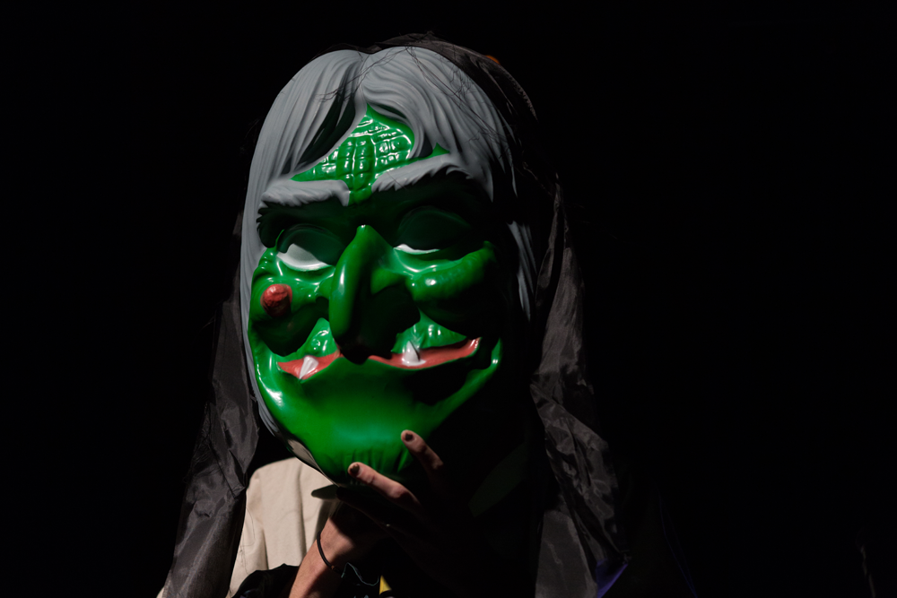 Sgaire Wood wearing a large green and grey witch mask