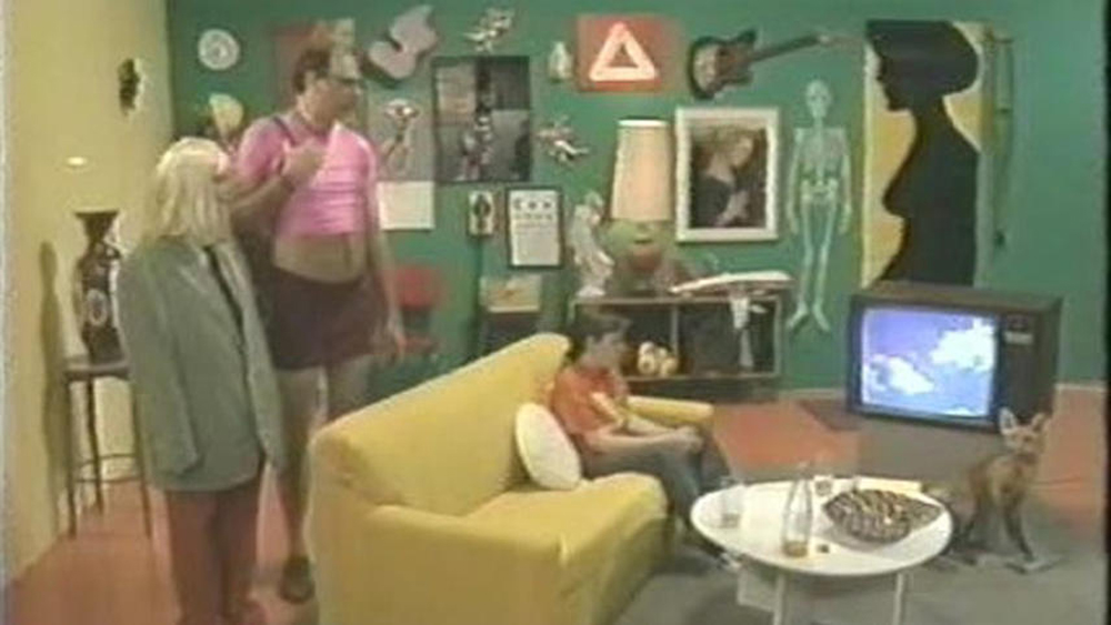 A film still of a set of a living room filled with pictures and a couple
