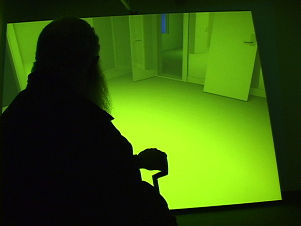 A silhouette of Delany in front of screen where a room is lit with green light