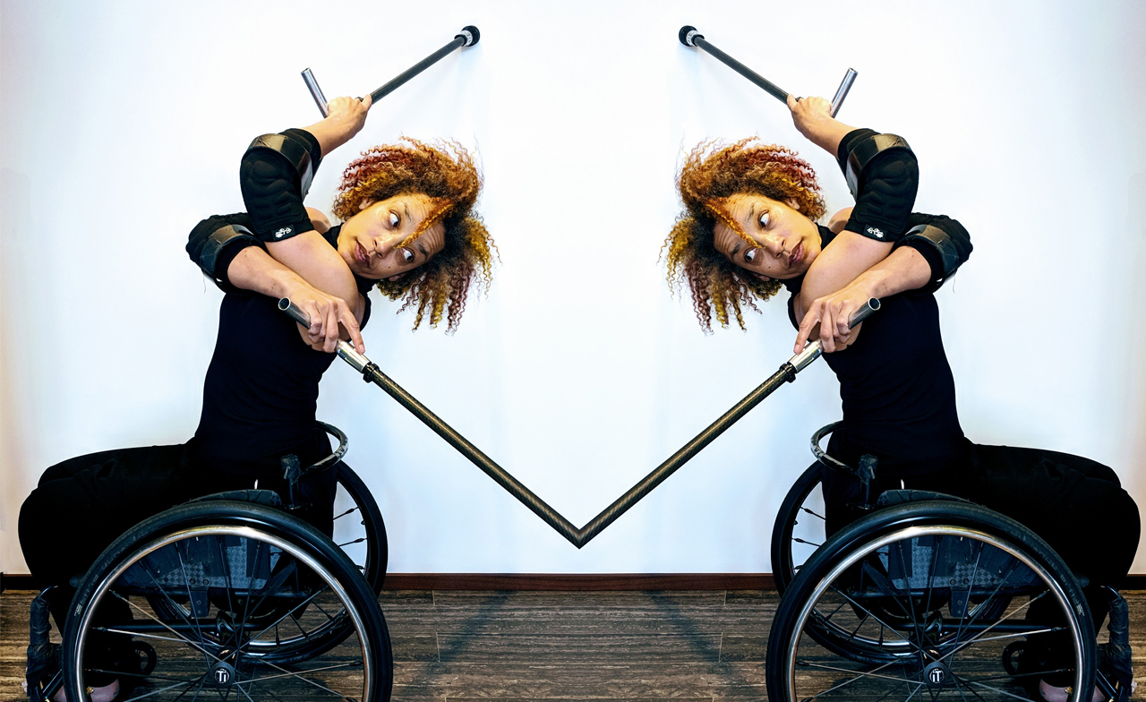 Seated in her wheelchair, Alice Sheppard, crosses her crutches behind her