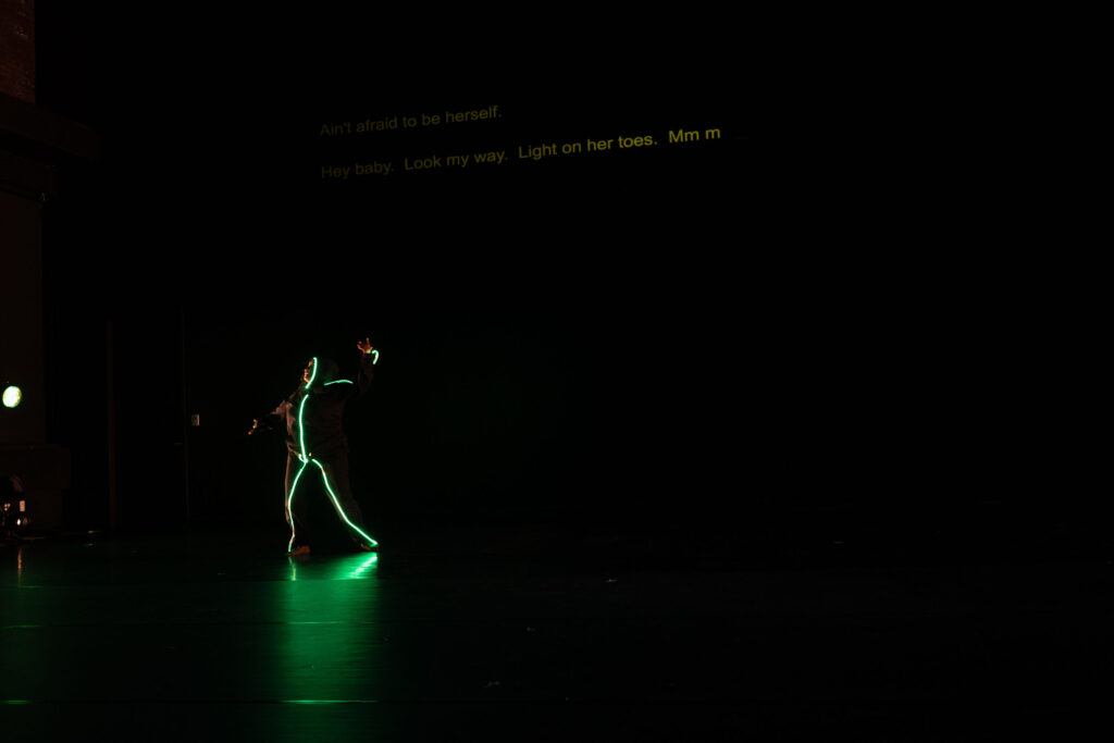 Dancer illuminated with fluorescent lights on their limbs
