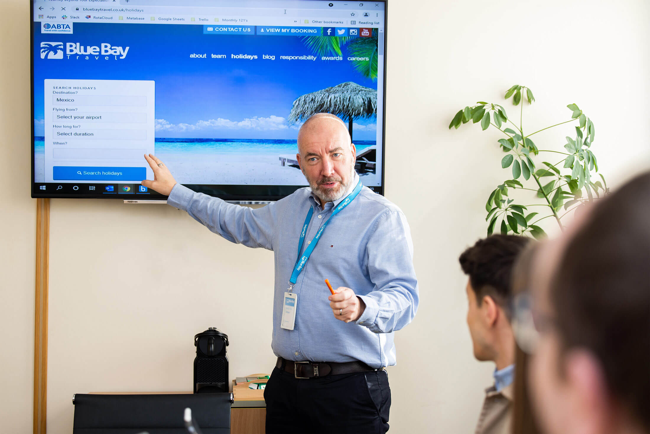 The Chief Executive Officer in front of a large television screen, presenting