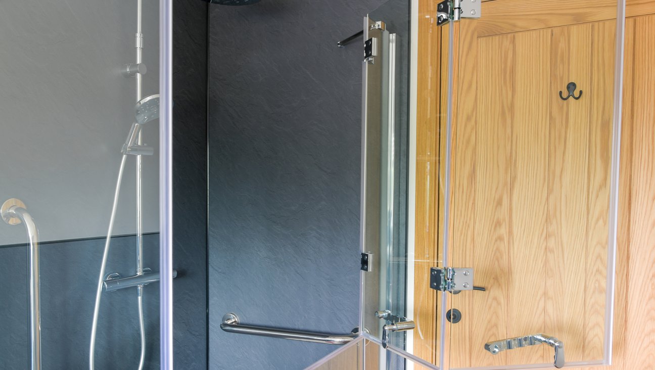 

                                        Shower screen, with top half open against an Oak door