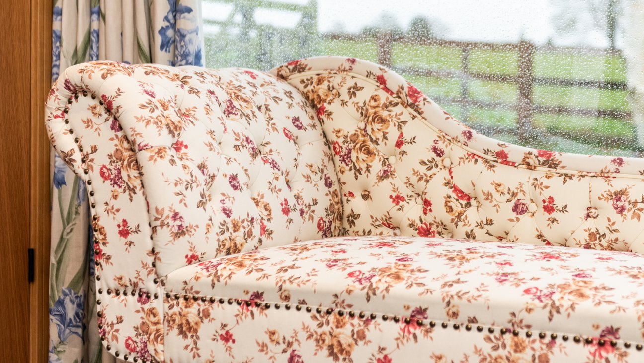 

                                        Chinz chaise longue against floor to ceiling windows looking out in to a garden with fields and trees beyond