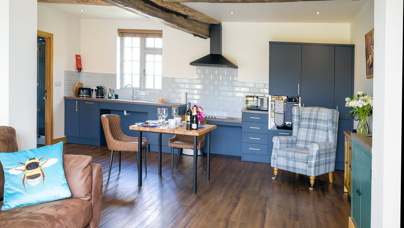 

                                        Kitchen area in background of white room, with a set table in foreground, and a squishy grey tweed chair.